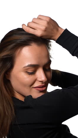 woman with hairstyle trembling from laugh. smiling positively and being in great mood while standing over white background. vertical video