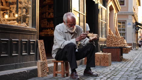 elderly wood carver in european alley