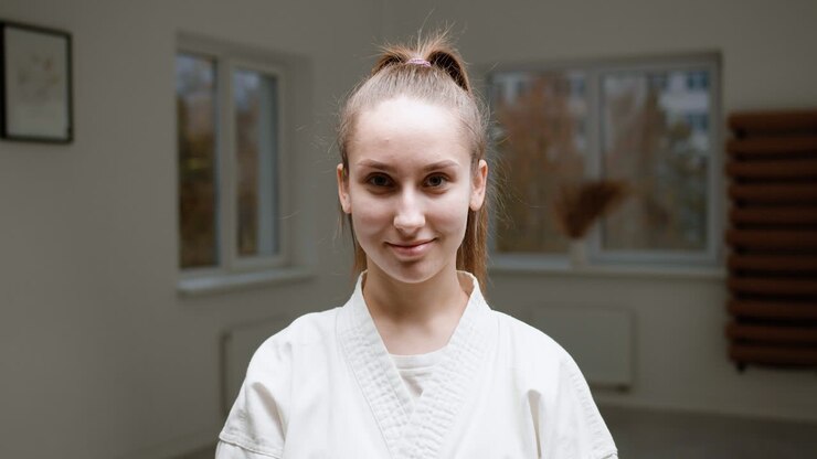 Caucasian female teacher in white kimono in martial arts class