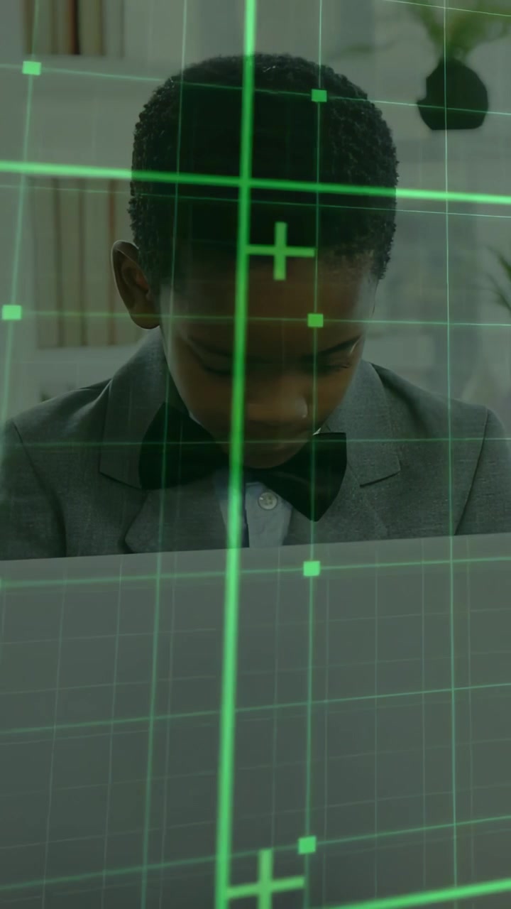 Vertical video: Boy in suit leaning, typing laptop, camera cropping, green grid overlaying learning