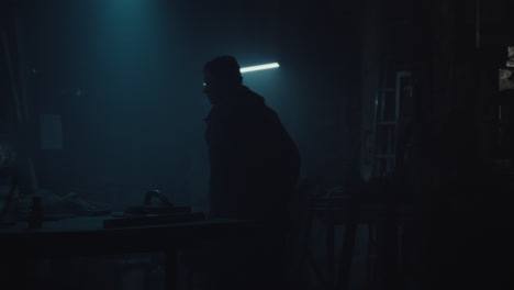 a man enters the dark workshop, turns on the lights and unveils a bomb