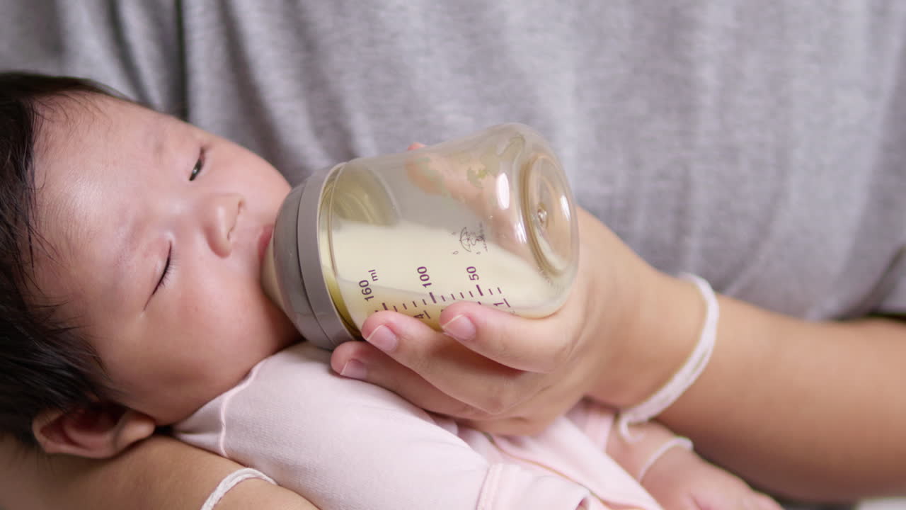 Mother Feeding 2-Month-Old Baby Girl: Slow Motion Capture of Baby Drinking a Large Amount of Milk from a Bottle