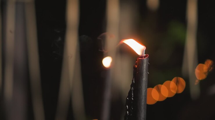 Candela nera accesa in giardino di notte
