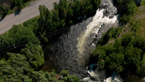 Drone-Volando-Sobre-Un-Flujo-Rápido-Debajo-De-Un-Puente-Y-Luego-Revelando-La-Inmensidad-Del-Lago-En-Un-Día-Soleado