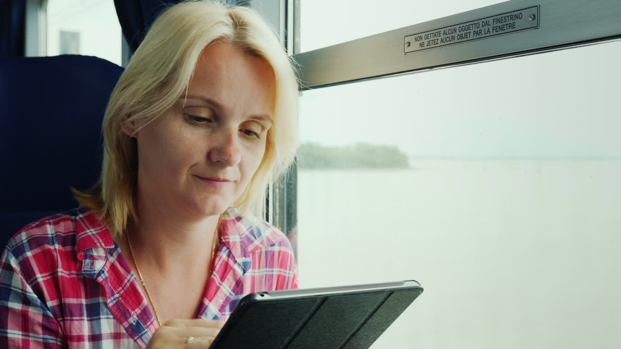 mujer usando una tableta junto a la ventana de tain