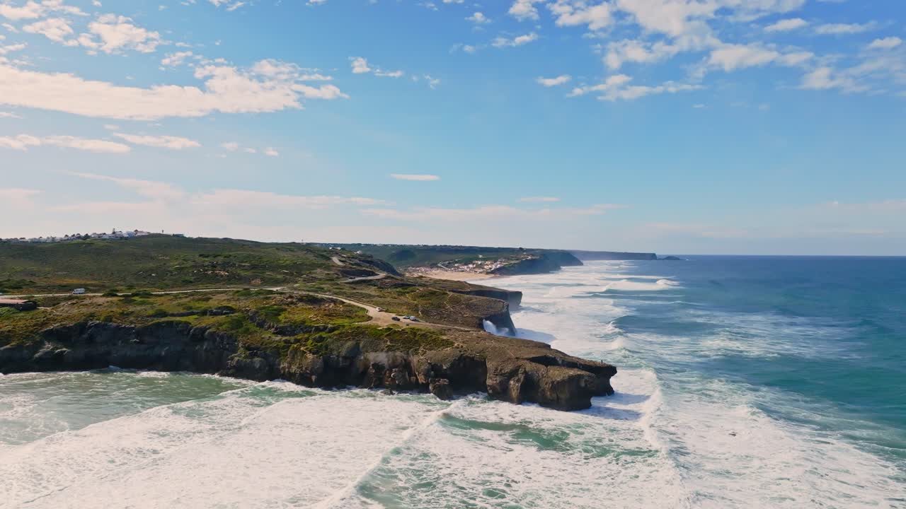 Portugal's coastline from above, as waves relentlessly strike the weathered cliffs. The aerial view captures the vibrant hues of the Atlantic's waters against the contrast of the rugged terrain.