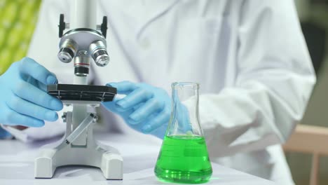closeup of biologist hands using microscope analyzing genetic mutation on plant. chemist specialist examining gmo test while working in pharmaceutical lab at ecology expertise