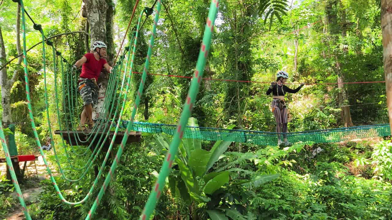 Couple enjoying a treetop adventure course in a tropical forest