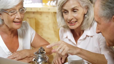 senior friends discussing over a laptop in cafe 4k