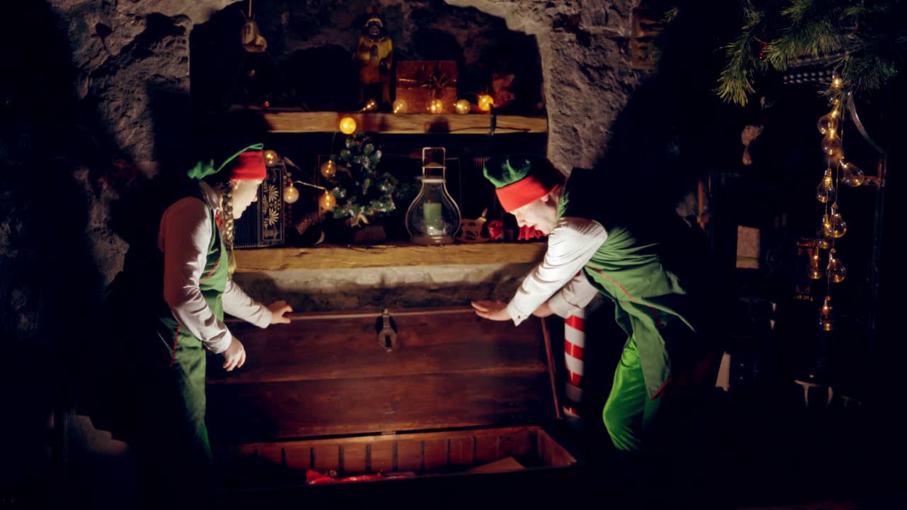 Elves opening magic gift box. Surprised elf helper of Santa opening magic Christmas box