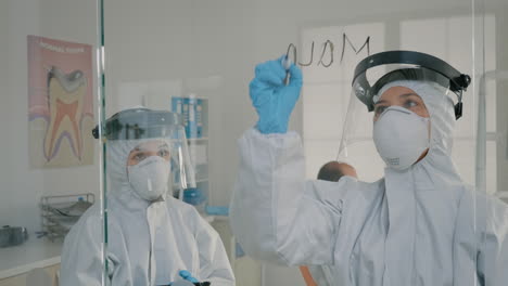 dental specialists analyzing tablet screen and writing on glass