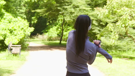 Young-Woman-Stretching-Before-Exercising-Running-Through-City-Park-Wearing-Wireless-Earbuds