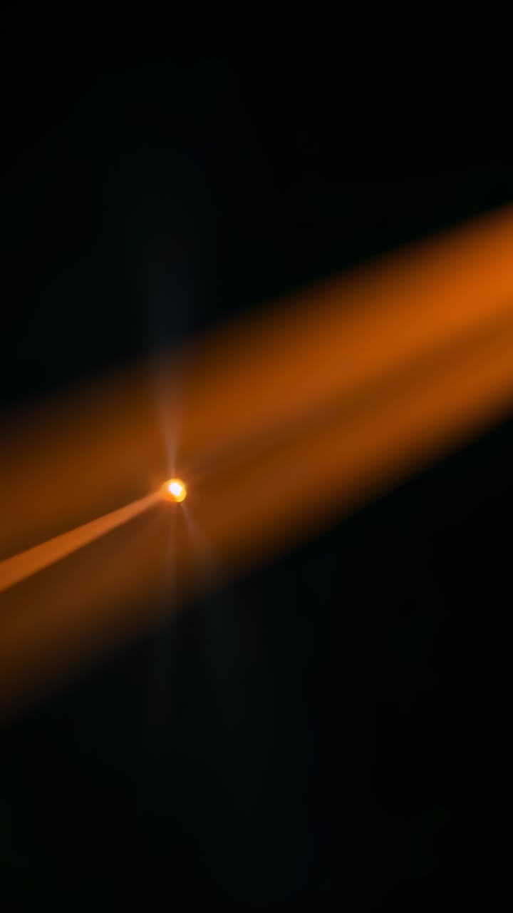 Vertical video: Second frame showing bright orange point with twin diagonal streaks forming band