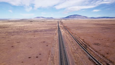 Drohnenaufnahme-über-Einer-Wüstenautobahn-Mit-Fahrendem-Sattelschlepper-Und-Auto