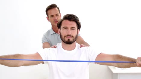 physiotherapist checking patients shoulders with resistance band