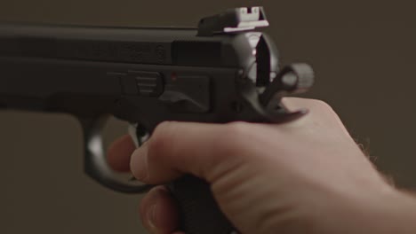 pulgar volteando hacia abajo el pestillo de seguridad de una pistola de 9 mm y disparando en seco - primer plano