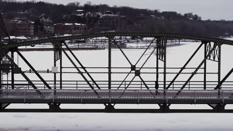 silhouetted against fresh white snow, a man walks across the arcola high bridge in stillwater, minnesota