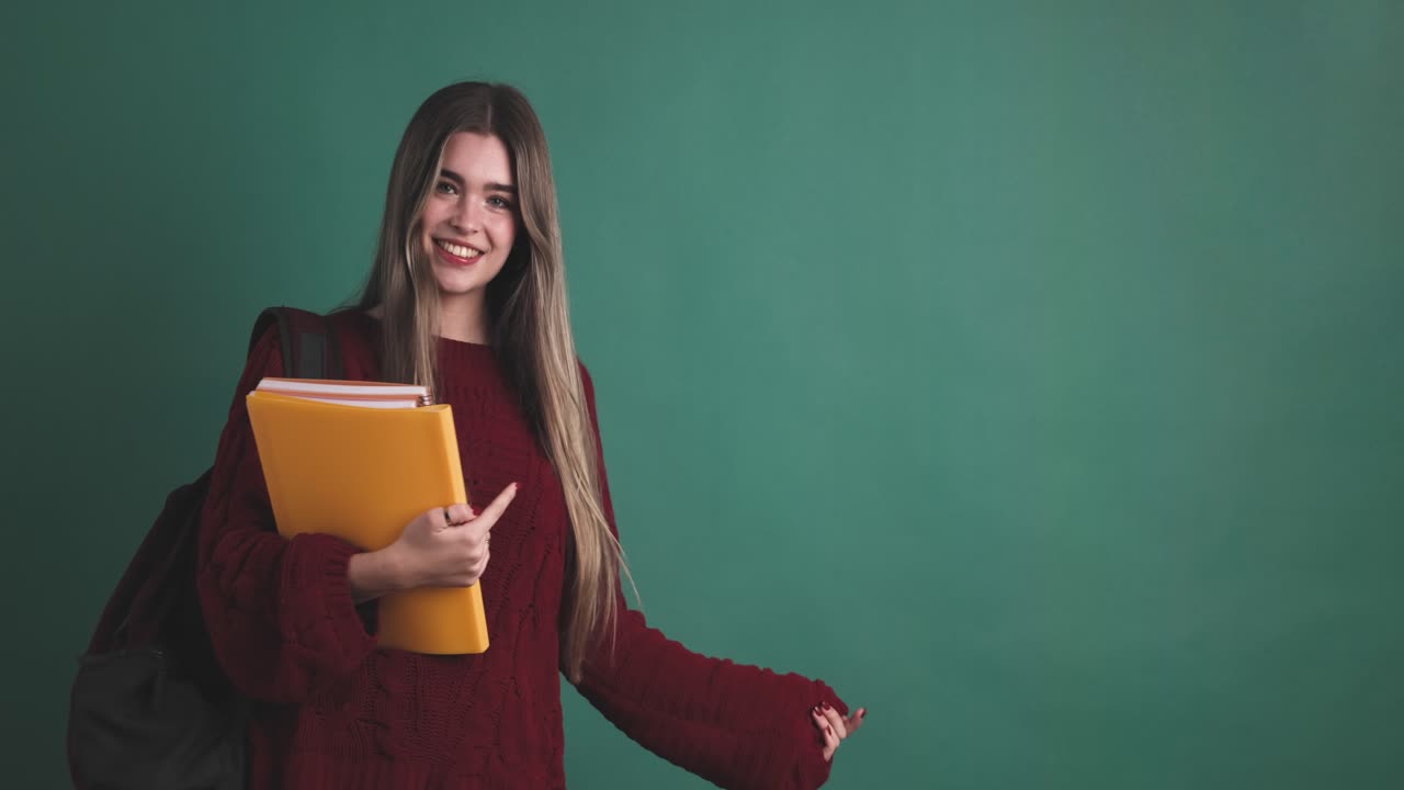 Happy young woman student showing empty space on wall