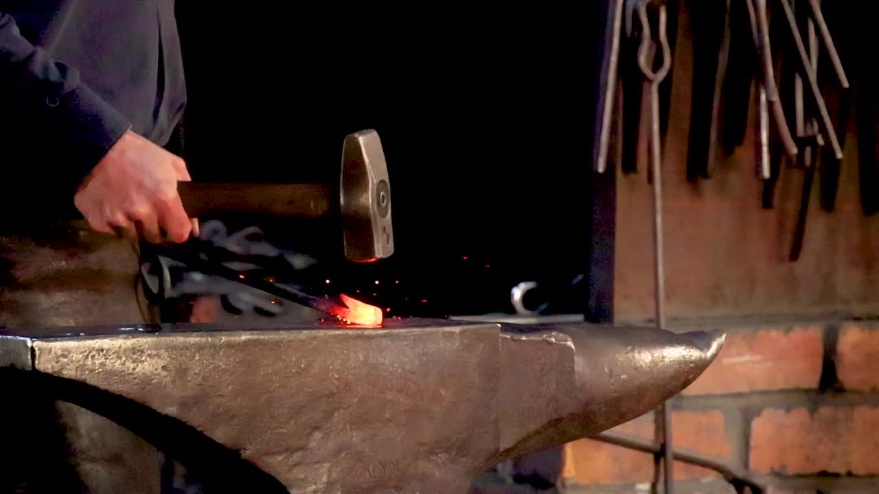 Close-up of a blacksmith hammering glowing metal on an anvil, highlighting precision and skill.