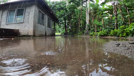 rainfall splashing forming ripples on the ground outside the house - low-level shot