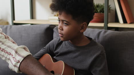 boy learning how to play the ukulele