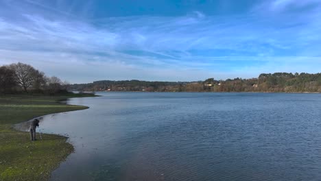 Flying-Towards-Travel-Photographer-Capturing-Lake-Scenery-In-Daytime