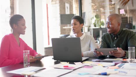 African-american-colleagues-with-documents-on-table-using-laptop-in-office,-slow-motion