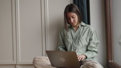 woman working on laptop at home by the window