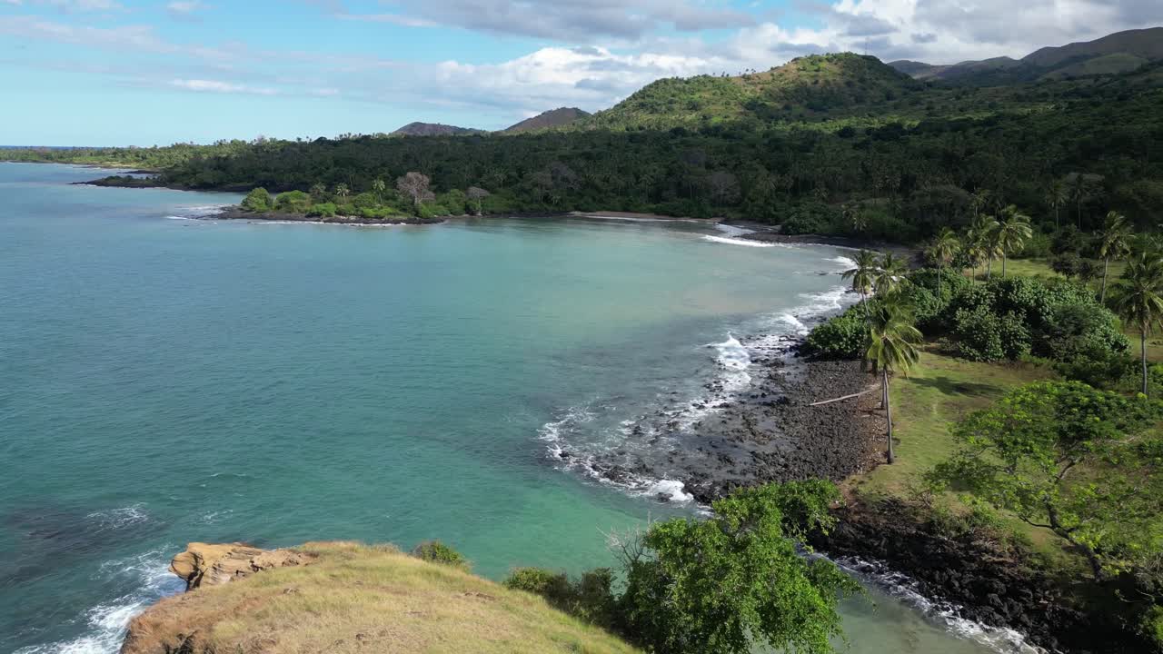 vista de un dron de una costa tropical con colinas verdes y palmeras en la gran comora