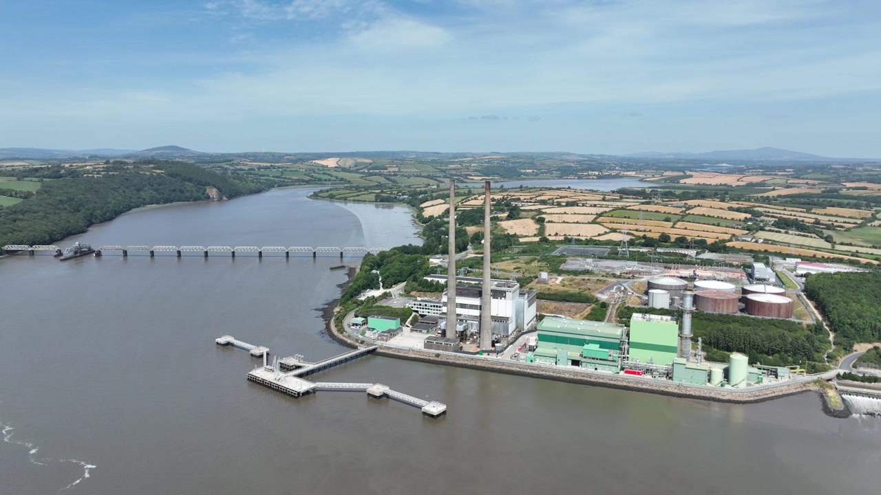 Impianto industriale di generazione di energia che si affaccia sull'estuario del fiume Suir, Contea di Wexford, Irlanda, filmato da un volo di drone cinematico e fluido.