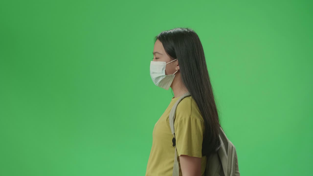 Teenage Girl Wearing a Mask and Backpack Walking in Profile View