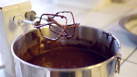 measuring and pouring vanilla extract into a mixing bowl of delicious vegan chocolate cake batter with an electric mixer