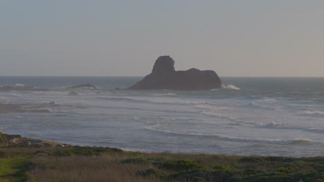 time lapse of a huge bolder near the shore on the pacific coast with fast moving waves crashing around it