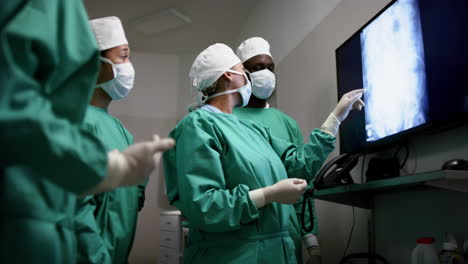 diverse surgeons discussing with x-ray scans in operating theatre at hospital, slow motion