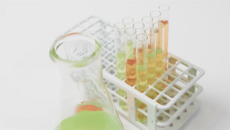 coloured liquids in flasks with test tubes in stand on white background, slow motion