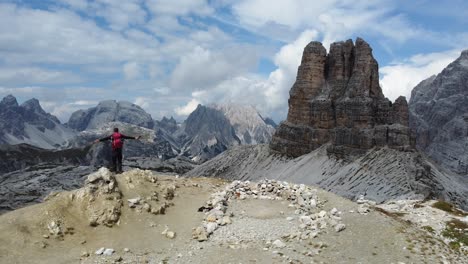 a hiker standing alone in the mountains and celebrating an adventurous and successful hike in the dolomites in italy - south tyrol