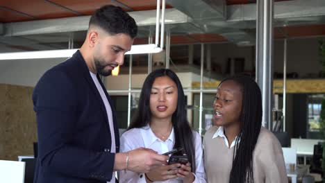 company of diverse coworkers using smartphone together in office