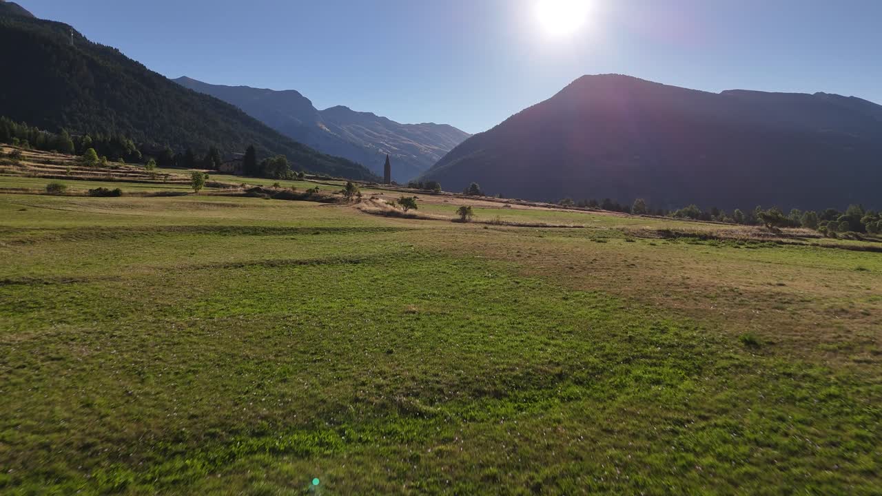 Drone che vola a bassa quota verso una chiesa in una valle montana in 4K