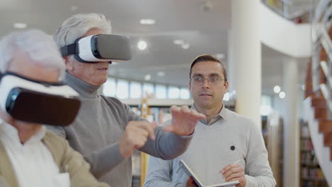 Ältere-Menschen-Mit-VR-Brille-In-Der-Bibliothek-Mit-Lehrer