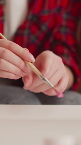 female artist shakes off drops of pink paint into water to make ebru picture in workshop closeup slow motion. oriental tradition of art and creation