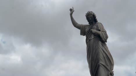 cemetary statue with a timelapsed background of clouds and sky