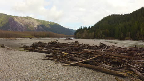 Aerial-view-flying-low-over-driftwood-on-a-scenic-Pacific-Northwest-mountain-river