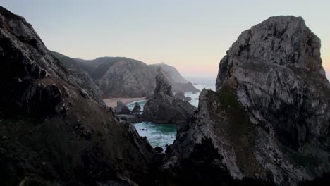 Drone-flying-through-rock-formation-with-hidden-beach-in-Portugal