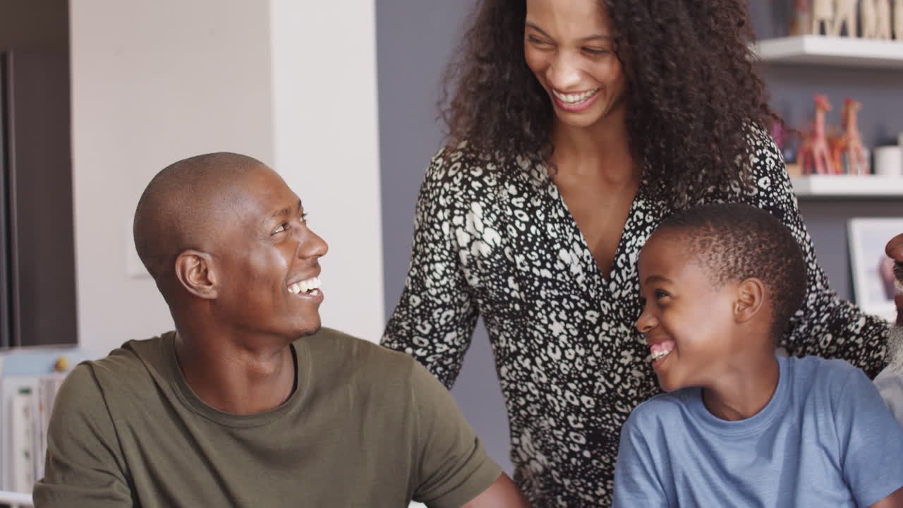 Famiglia multigenerazionale sorridente seduta attorno al tavolo a casa
