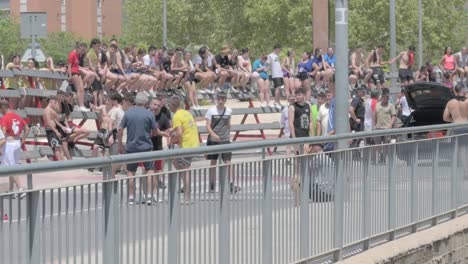 large crowd of young people gathered outdoors on a street with barriers