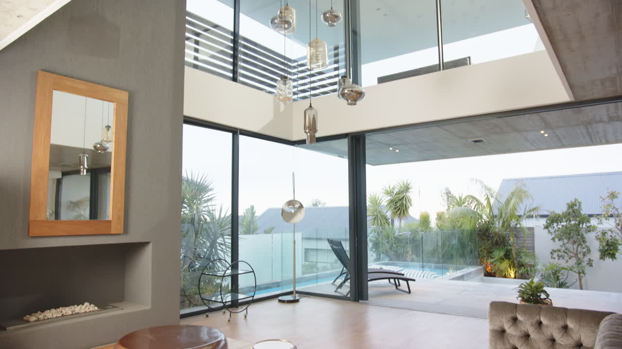 Modern living room with large windows overlooking pool and outdoor seating area, at home