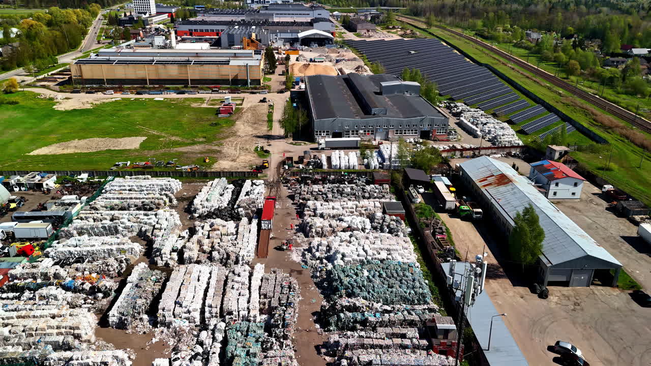Landfill waste site with trash compactors beside solar panels, aerial view from above