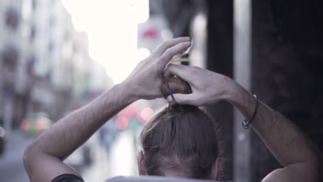 man adjusting hair in city street