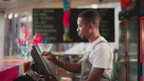 bearded salesman works on computer at counter. african american shop assistant inputs data in base after work shift. young cashier prepares bills for boss