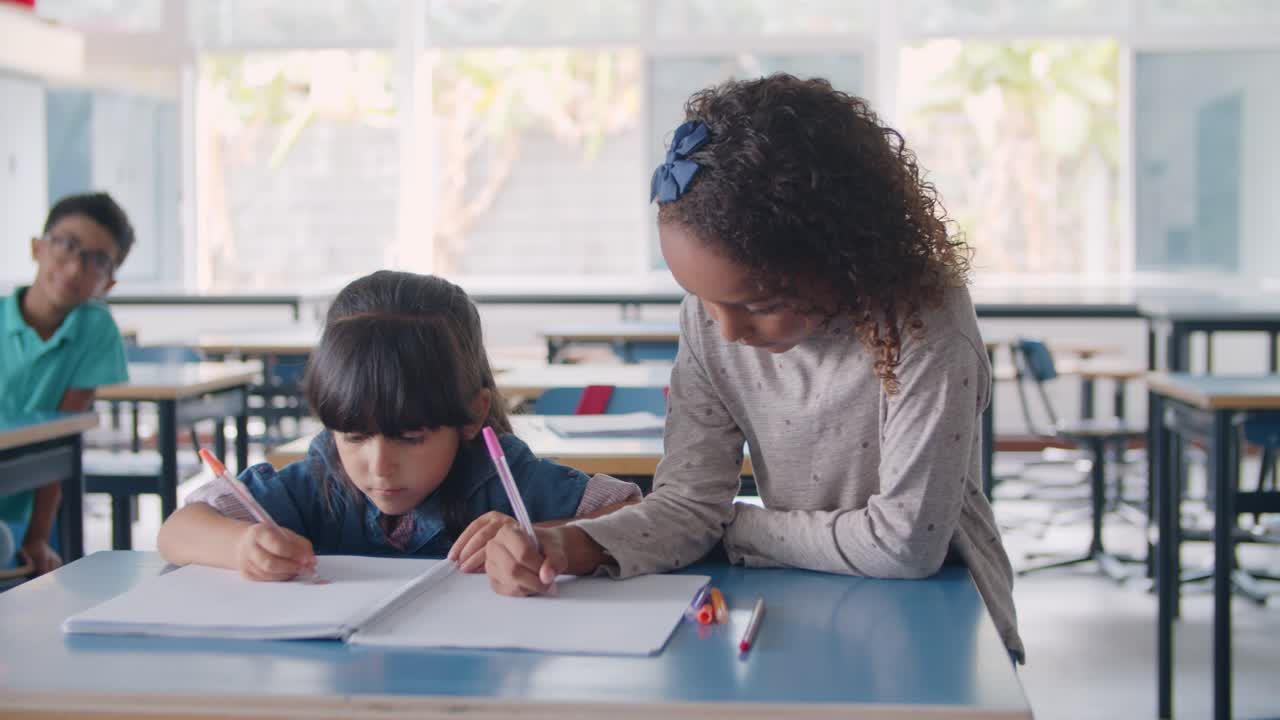 niñas de escuela primaria afroamericanas y latinas enfocadas dibujando en un cuaderno